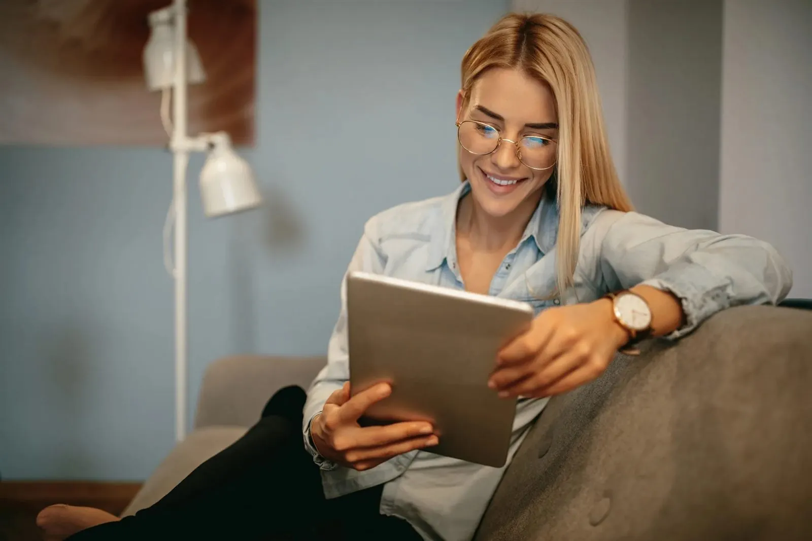 A licensed clinician smiles while reviewing a tablet in a relaxed office chair.